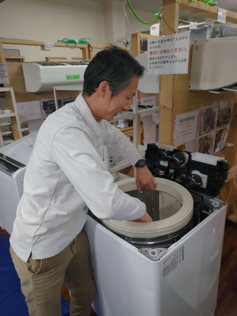縦型洗濯機の分解洗浄で洗濯槽を引き出す工程