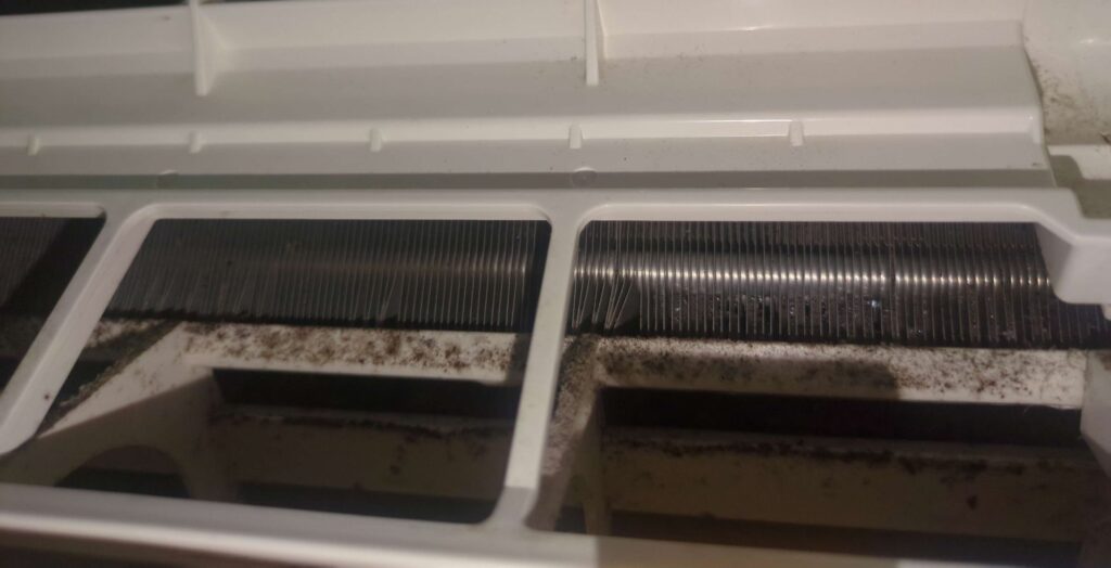 横浜市でエアコン分解洗浄前の熱交換器や本体カバーに埃やカビが付着している様子(梅雨時期)