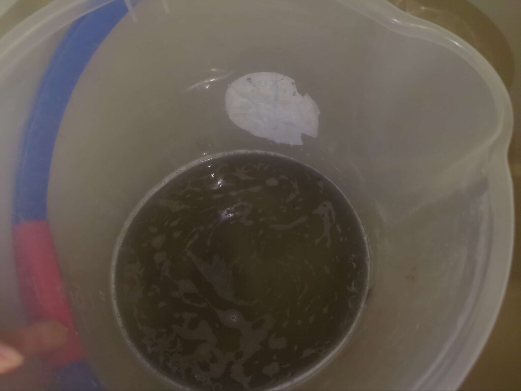 高圧洗浄後の黒カビを含んだ汚水
