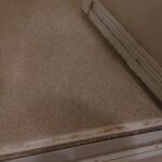 横浜市戸塚区で浴室クリーニングを行う前の、頑固な水垢がびっしりこびりついた浴室扉の様子