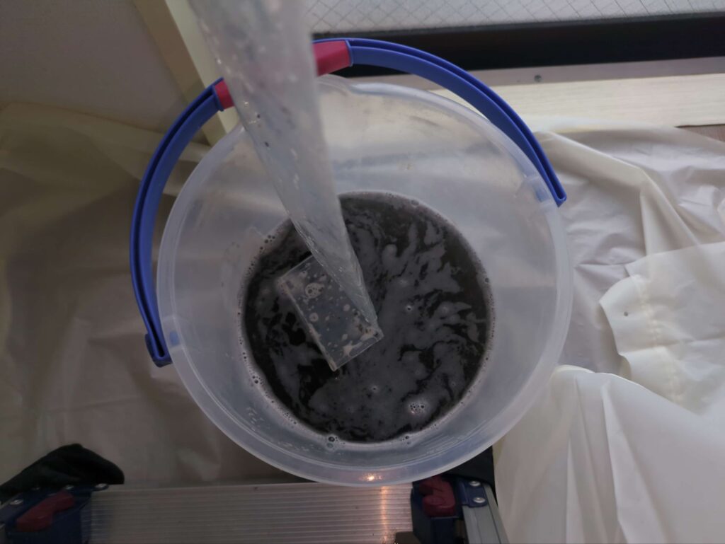 カビ汚れが送風口に付着したエアコンの分解洗浄後の黒カビで黒くなった汚水