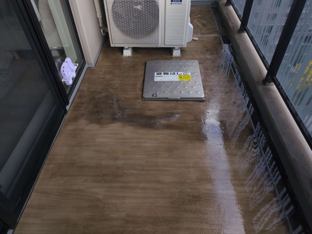 バルコニー洗浄の作業途中の綺麗になった面と汚れた面の写真