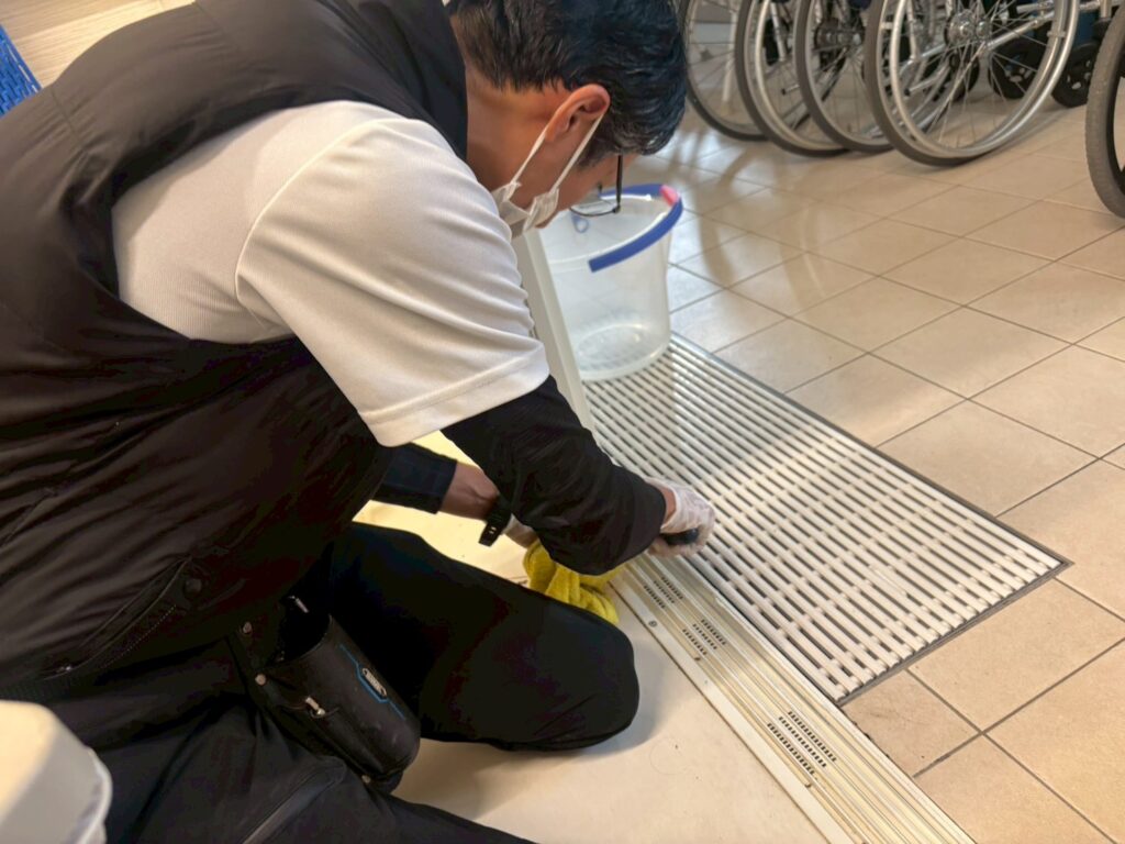 清掃ボランティアで浴室扉のレールを清掃している様子