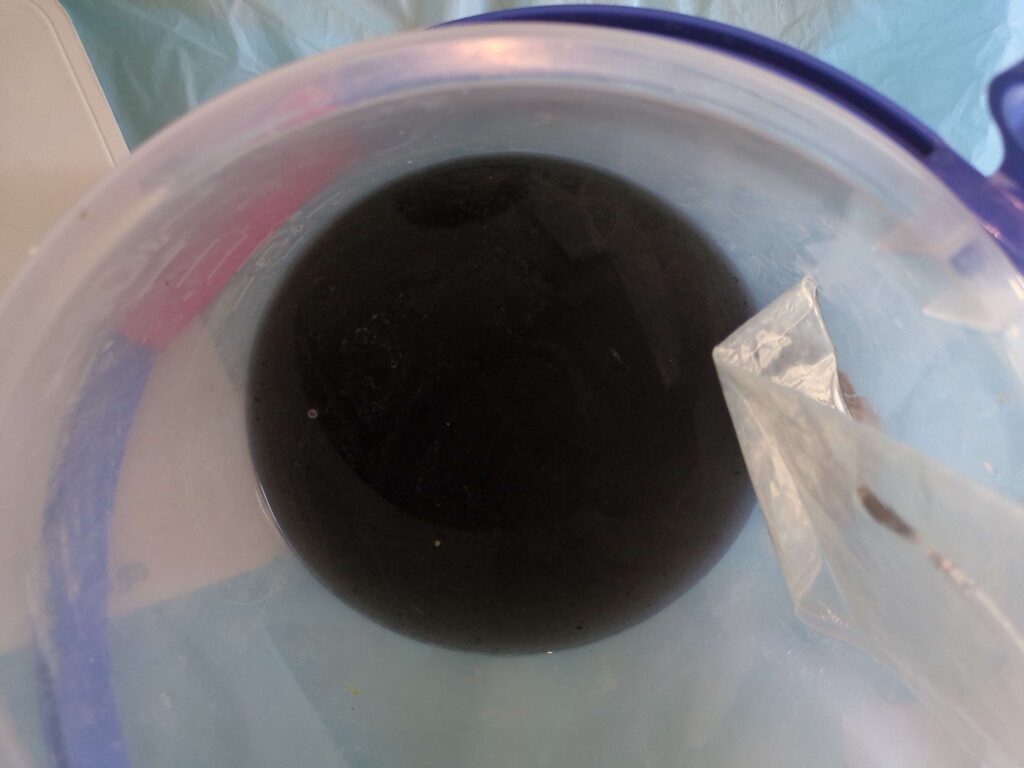 横浜市緑区でエアコンクリーニングした後の黒カビで真っ黒な汚水の様子