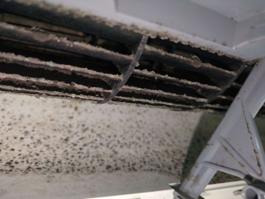 横浜市緑区で三菱電機製お掃除機能付きエアコンの分解洗浄前の黒カビで真っ黒な送風口の様子