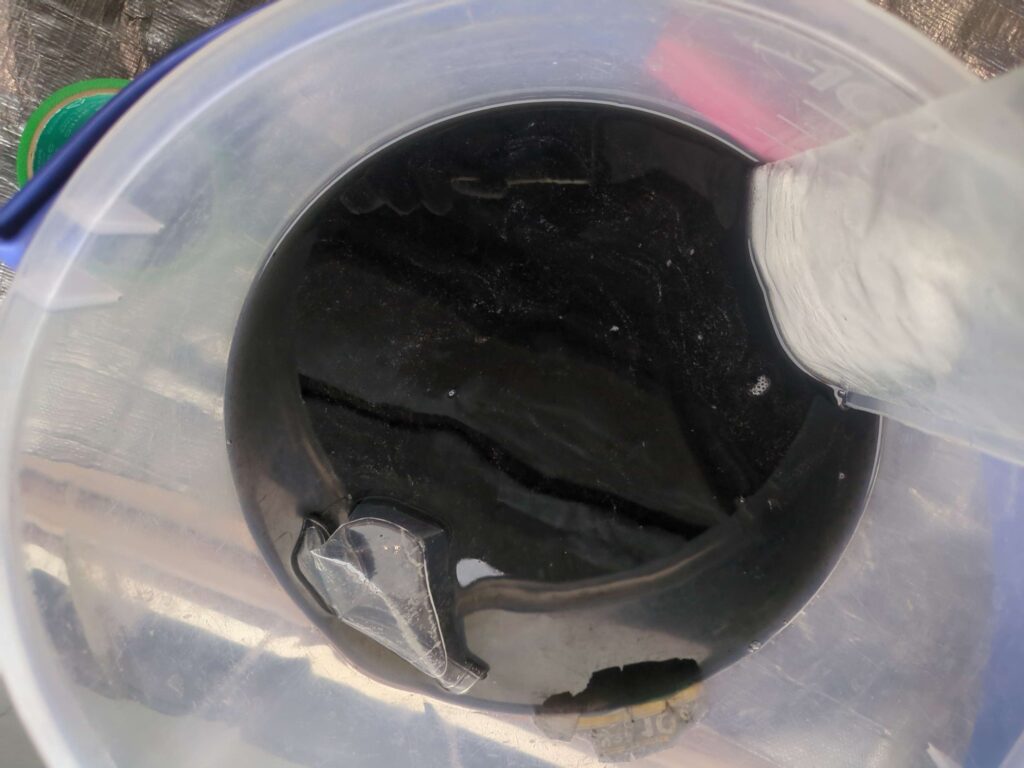 横浜市西区でシャープ製スタンダードエアコンの分解洗浄後の黒カビで真っ黒な汚水の様子